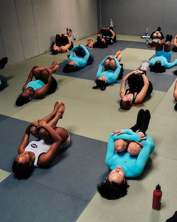 Aerial view of people in colorful athletic wear lying on yoga mats stretching in a fitness studio
