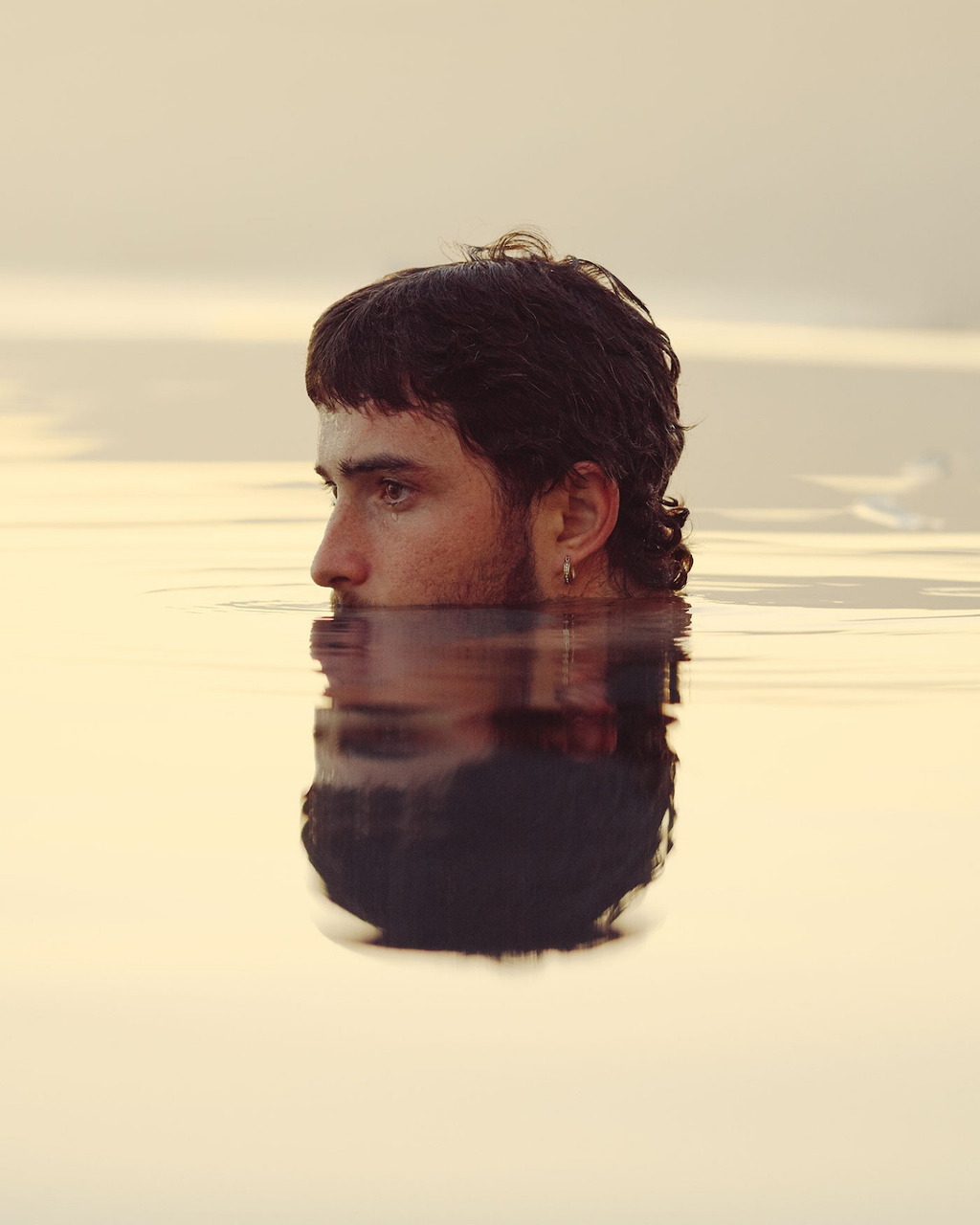 Man's head in still water with symmetrical reflection below the surface