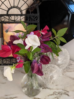 Bouquet of pink, purple, and white sweet pea flowers in a glass vase on marble surface