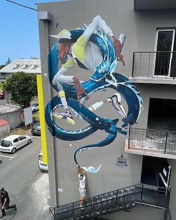 Large mural on building wall showing a figure dancing with a blue serpent-like dragon in Saint-Denis, France