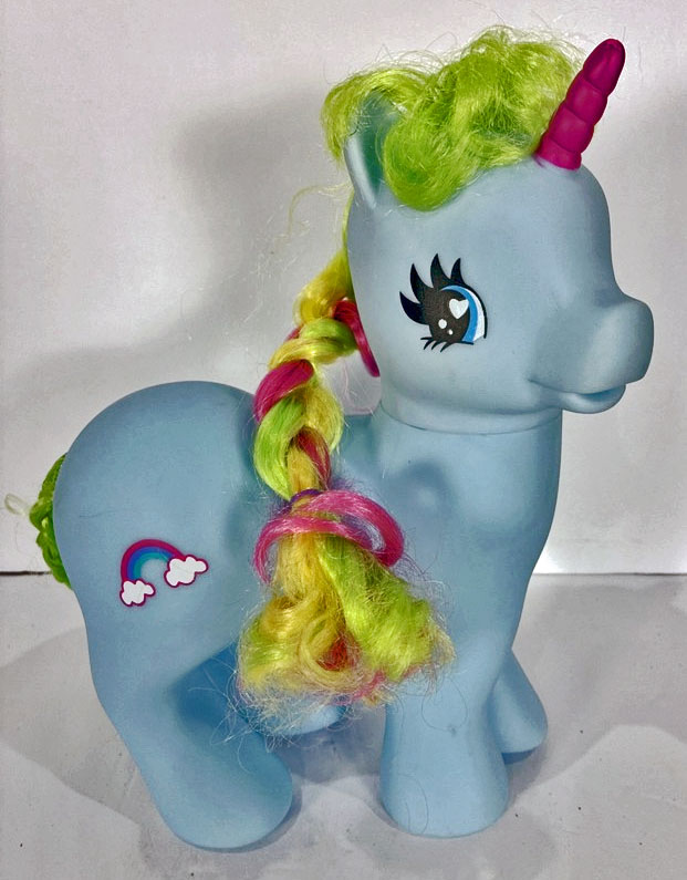 Light blue toy unicorn with pink horn and colorful braided mane on a white background