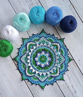 Blue, green, and white crochet mandala on wood with six yarn balls above