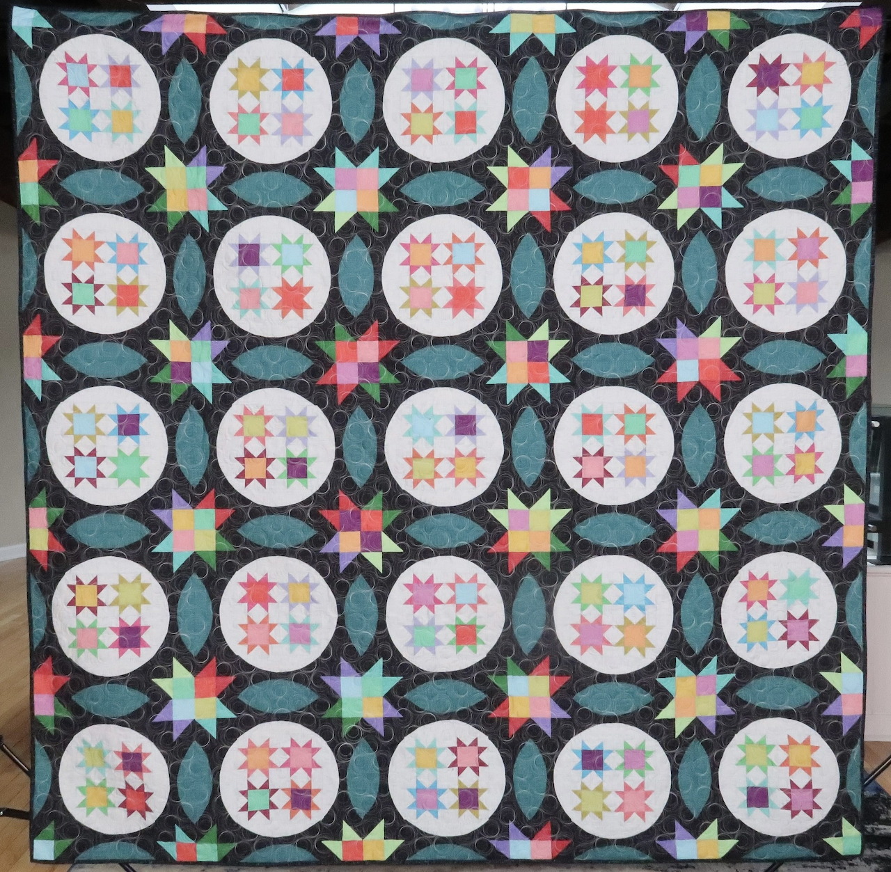 Colorful patchwork quilt with circular floral blocks and stars in a square layout