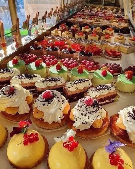 Bakery display case filled with assorted French pastries, tarts, and cakes topped with berries and cream