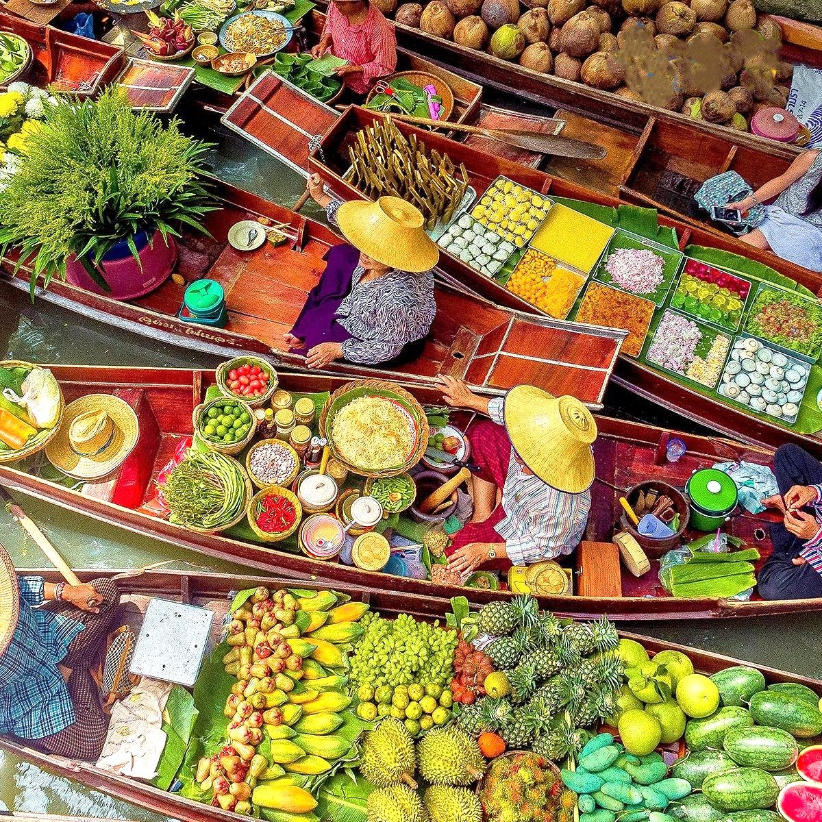 Aerial view of wooden boats loaded with colorful fruits, vegetables, and spices at a floating market