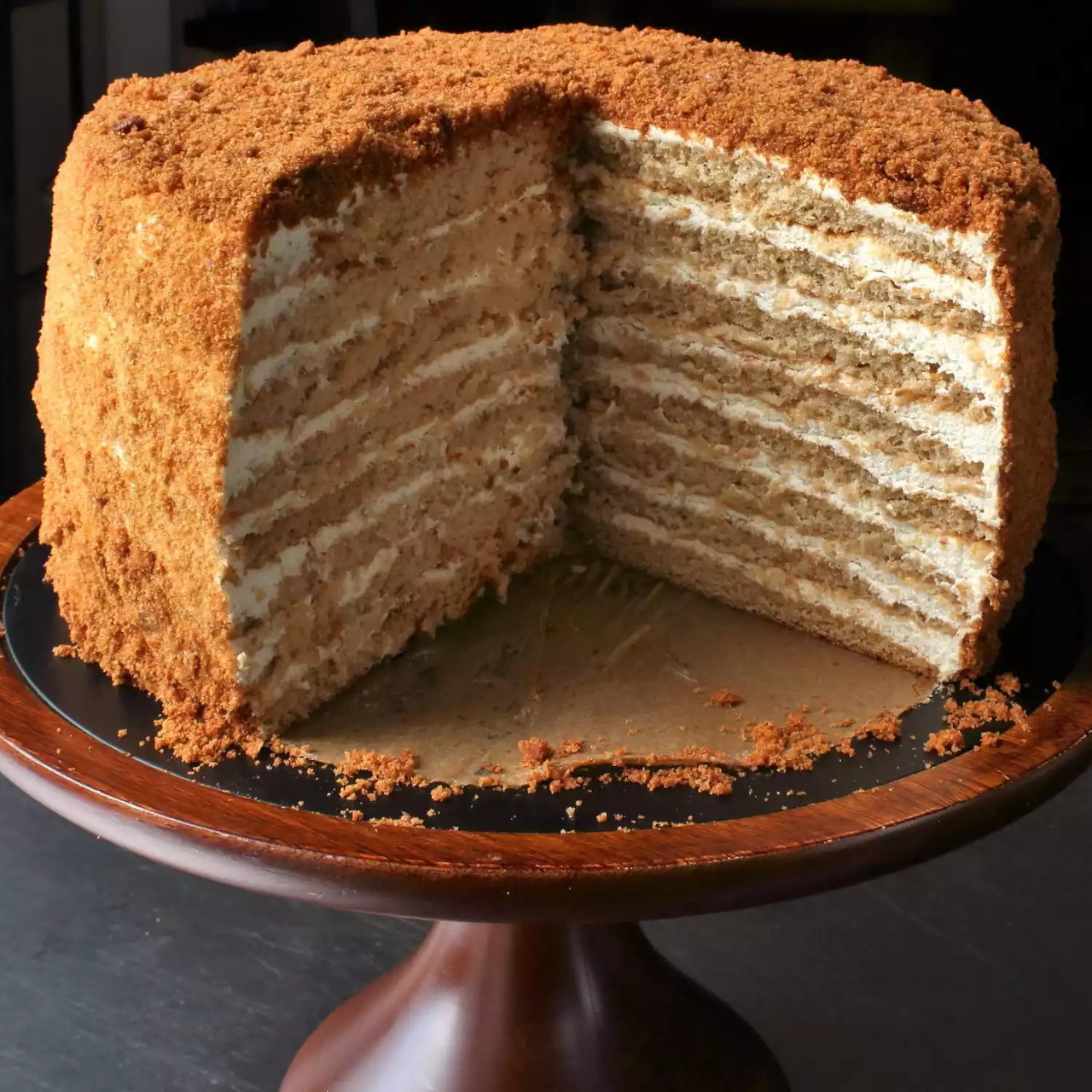 Sliced Russian honey cake with many thin layers and cream filling on wooden stand