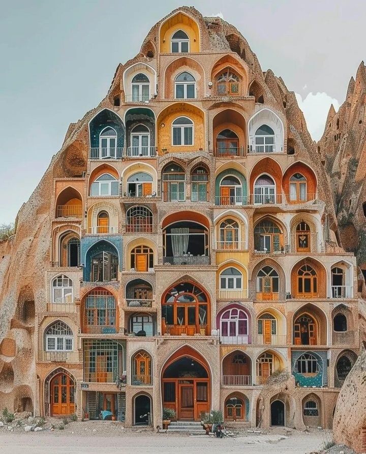 Rock-carved Cappadocia house facade with many colorful arched windows and doors