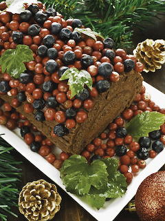 Christmas fruitcake loaf decorated with red berries, blueberries, holly leaves, and pinecones