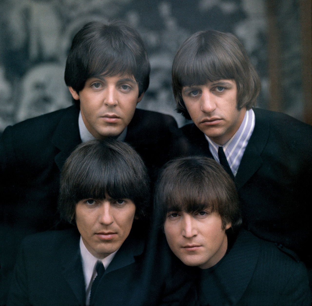 Portrait of The Beatles, four men with dark hair and suits looking at camera