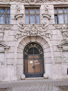Ornate stone arched entrance of Adria Palace with intricate Art Nouveau carvings and wrought-iron gate