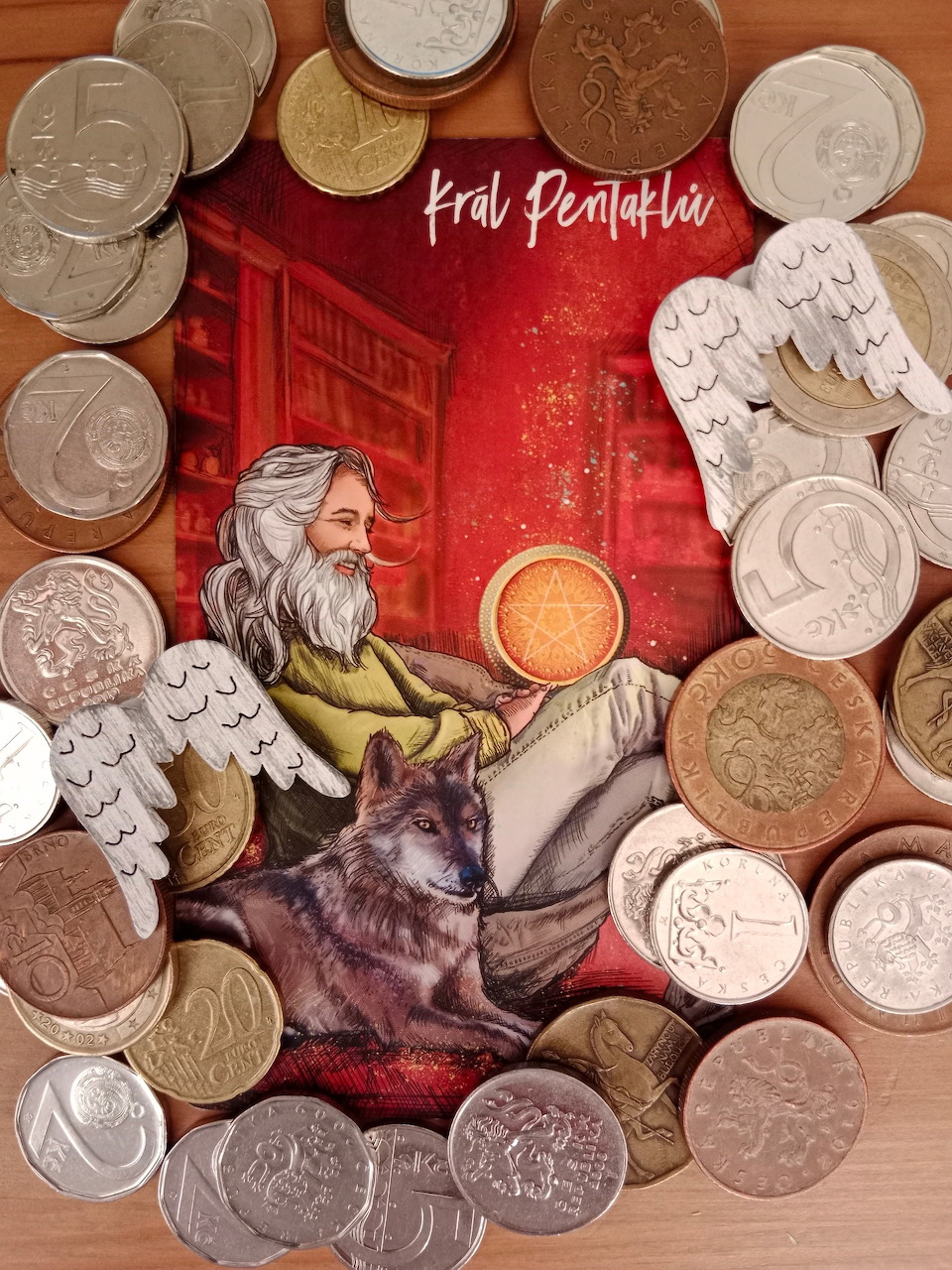 King of Pentacles tarot card surrounded by assorted coins on a wooden table