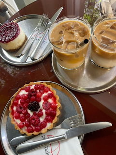 Two iced coffee drinks with desserts including raspberry tart and cheesecake on wooden table