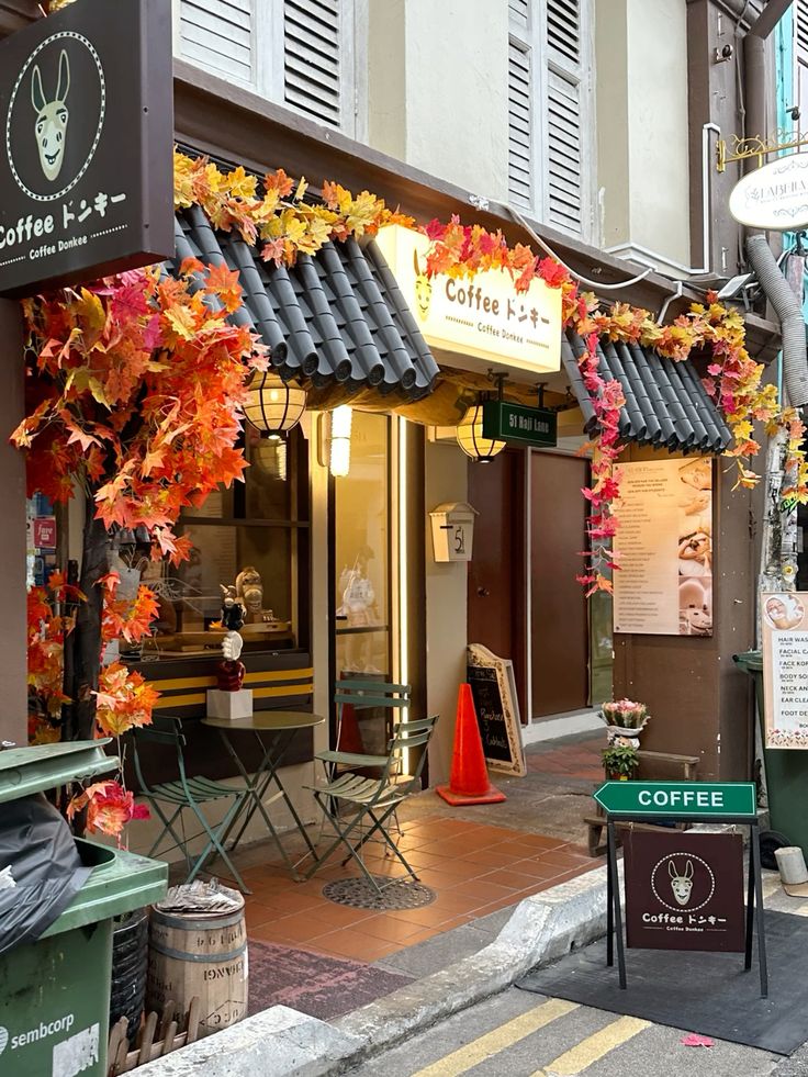 Coffee shop exterior decorated with colorful fall leaves garlands and outdoor bistro tables on a narrow street