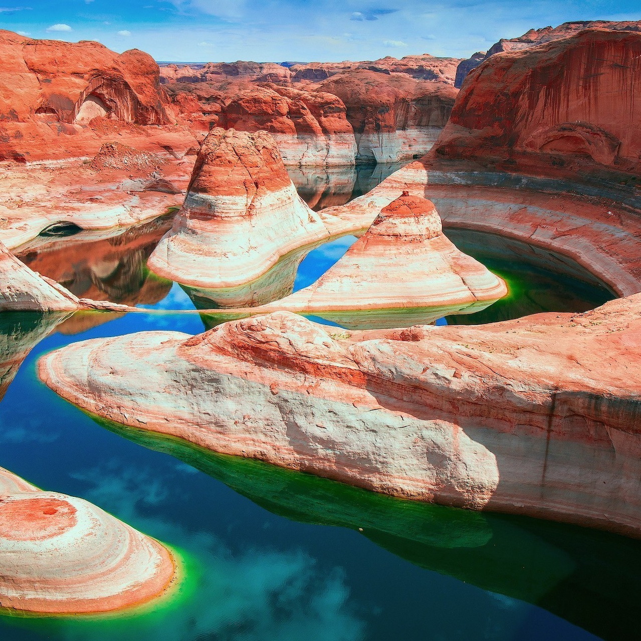 Aerial view of turquoise pools winding through striped red and white sandstone canyon formations