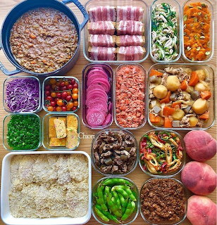 Overhead view of diverse meal prep containers with colorful prepared foods and ingredients