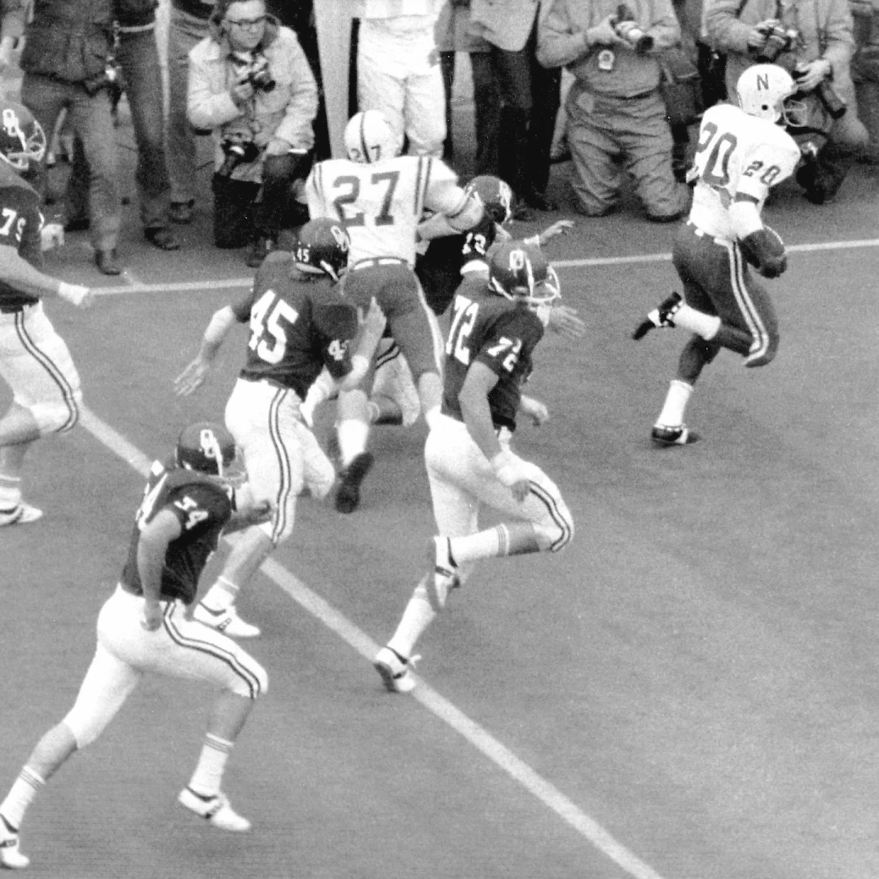 Black-and-white college football punt return with players running near the sideline