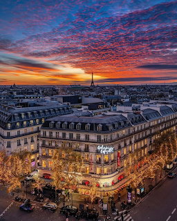 Aerial view of Galeries Lafayette Paris at sunset with Eiffel Tower in background and glowing city lights