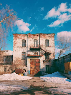 Abandoned brick warehouse building with snow on the ground and blue sky with clouds