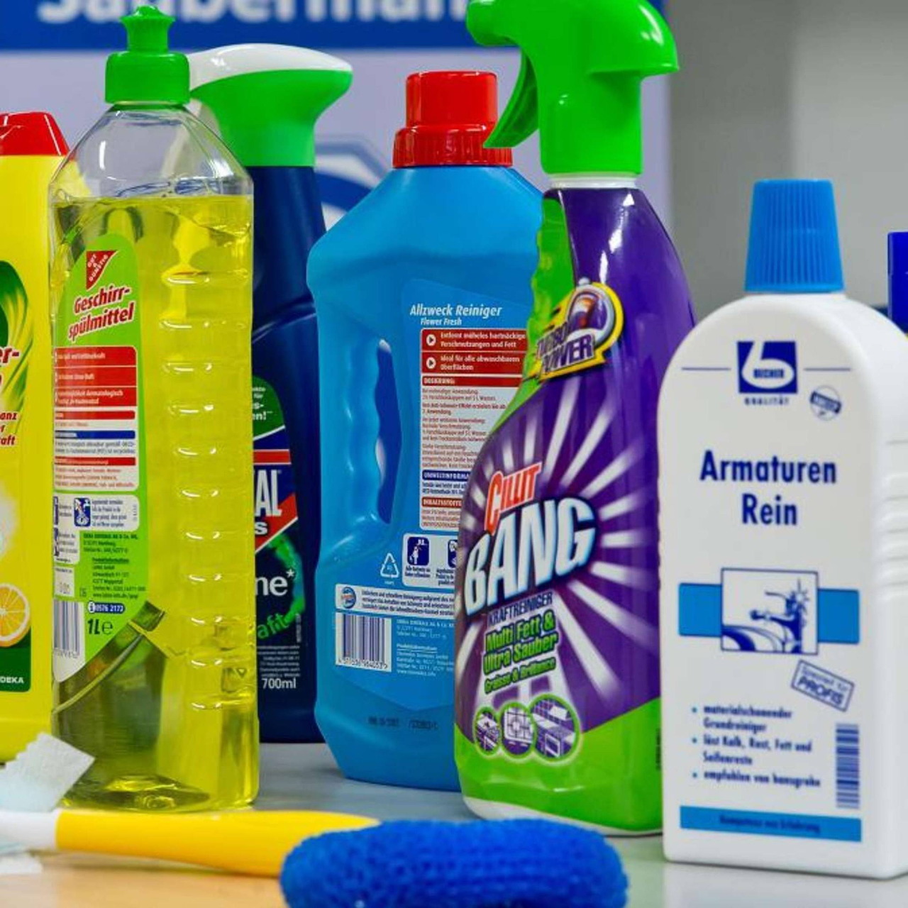 Various colorful cleaning product bottles and spray containers on a countertop