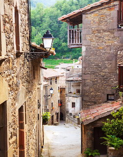 Narrow stone street in an old Catalan village with rustic houses and a wall lamp