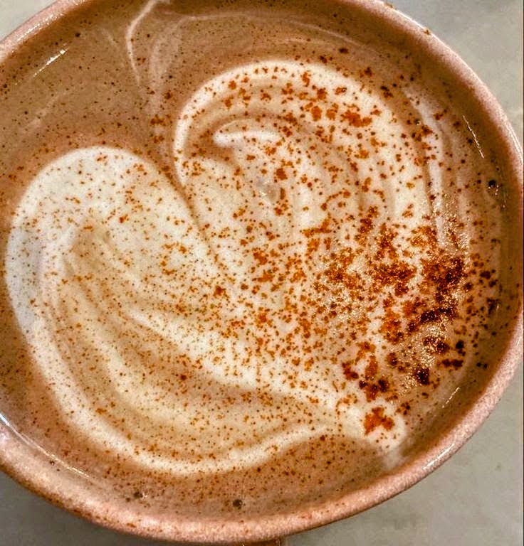 Latte with heart foam art and cocoa powder in pink cup