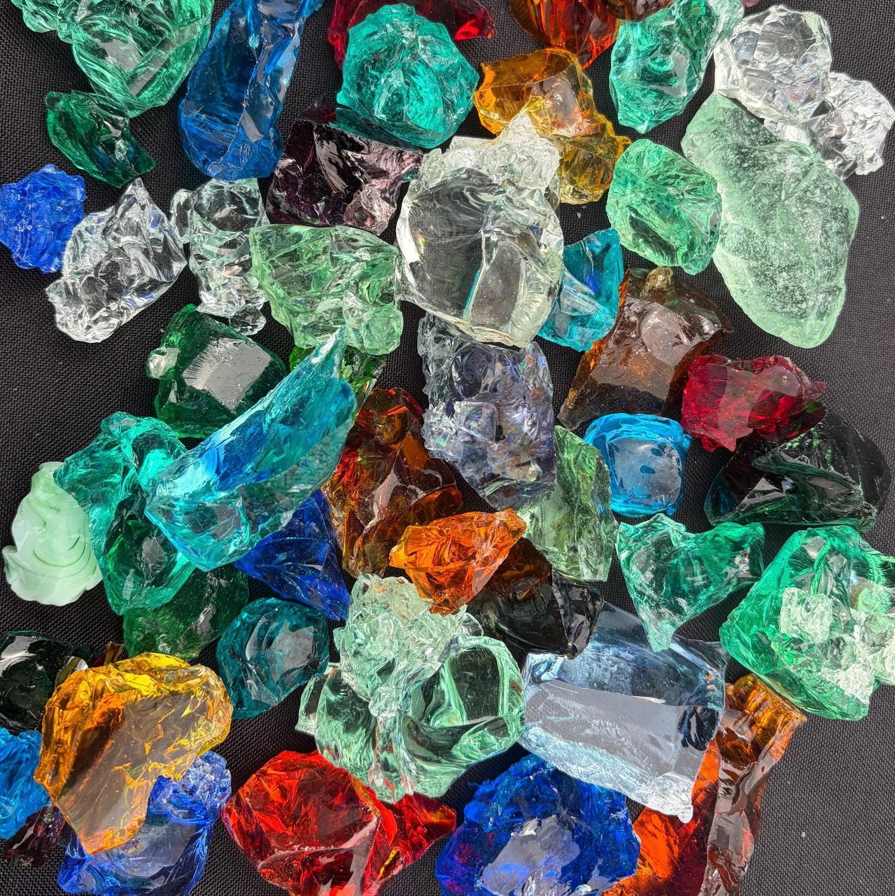 Assortment of colorful translucent glass chunks in various shapes and colors on dark background