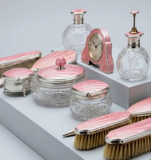 Vintage Art Deco vanity set with pink enamel crystal jars, perfume bottles, brushes, and a small clock