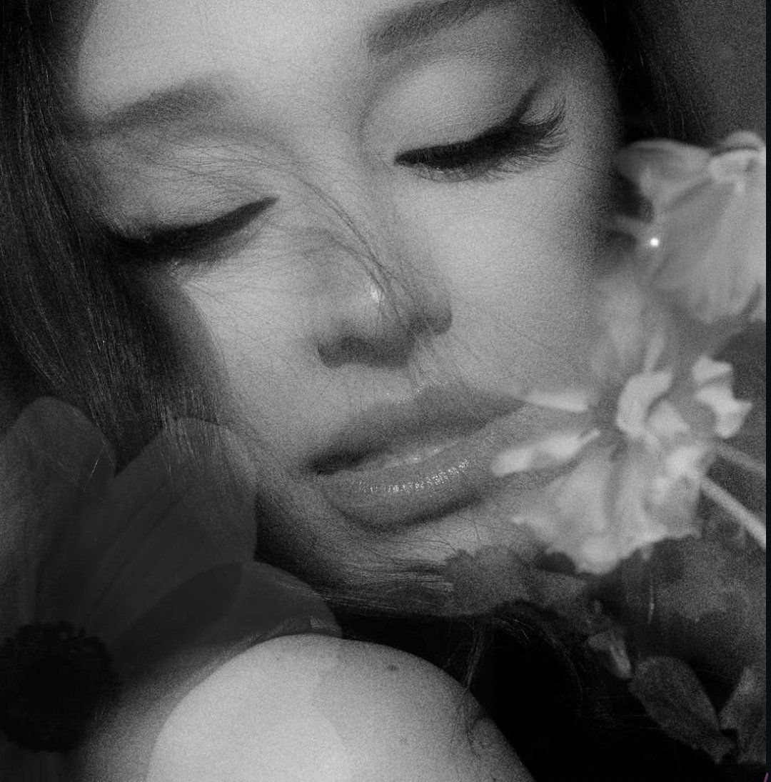 Black-and-white close-up of a woman with closed eyes and flowers near her face