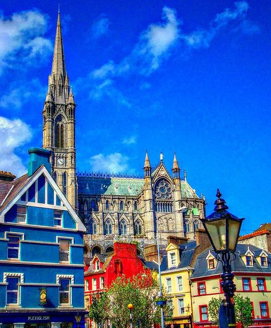 Gothic cathedral towering over colorful town buildings beneath a bright blue sky