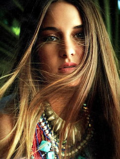 Close-up portrait of young woman with long blonde hair wearing colorful bohemian necklaces and accessories