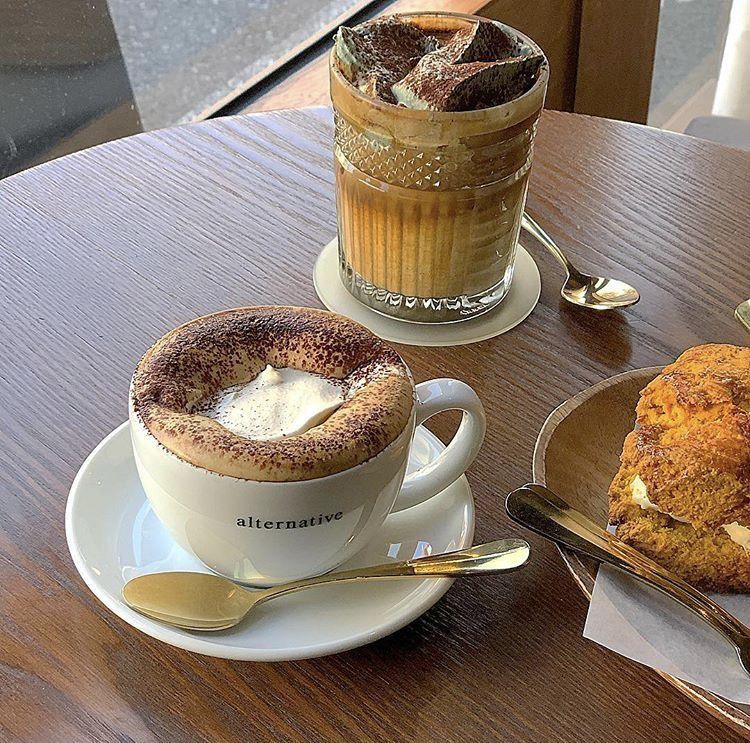 Cappuccino, iced coffee, and a pastry on a wooden cafe table