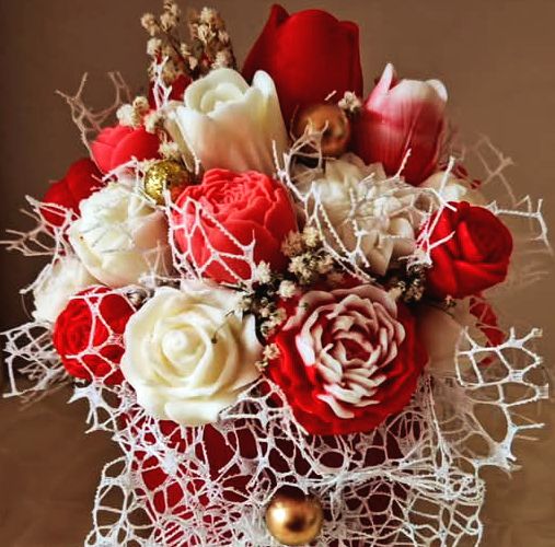 Red and white silk rose bouquet with decorative white netting on brown background