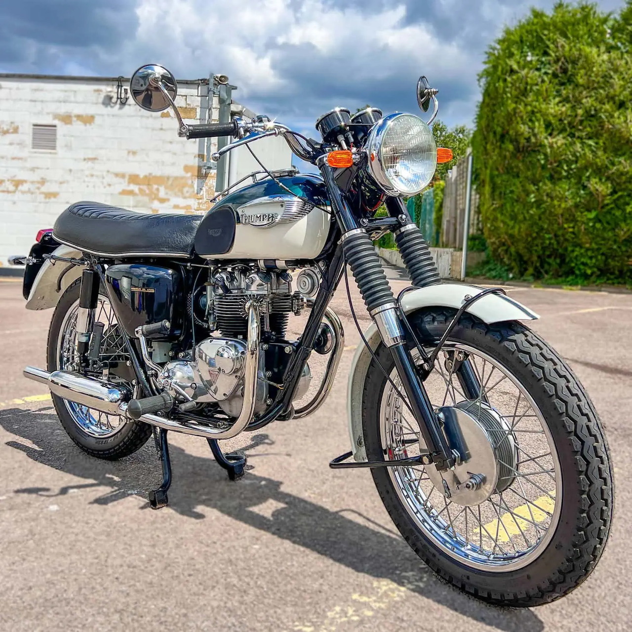 Classic Triumph T90 motorcycle with blue fuel tank and chrome accents on display outdoors