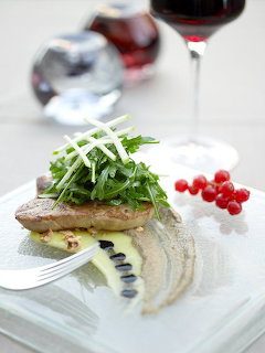 Plated gourmet fish dish with arugula and red currants on white square plate