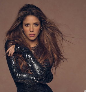 Shakira with long blonde wavy hair posing for a portrait