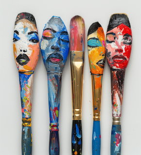 Five paintbrushes with vibrant abstract face portraits painted on handles