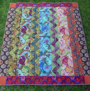 Vibrant patchwork quilt with vertical floral fabric strips on grass