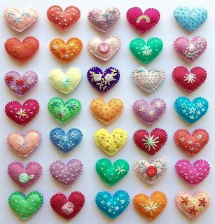 Grid of 35 handmade felt hearts in various colors with decorative stitching and embellishments