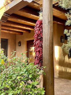 Red chile ristra hanging from wooden post at adobe building entrance in Santa Fe