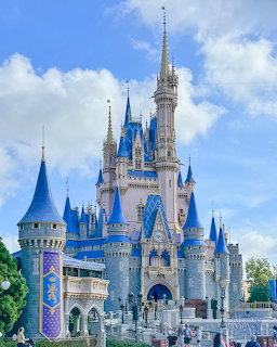 Cinderella Castle with blue turrets and white stone facades under a cloudy blue sky