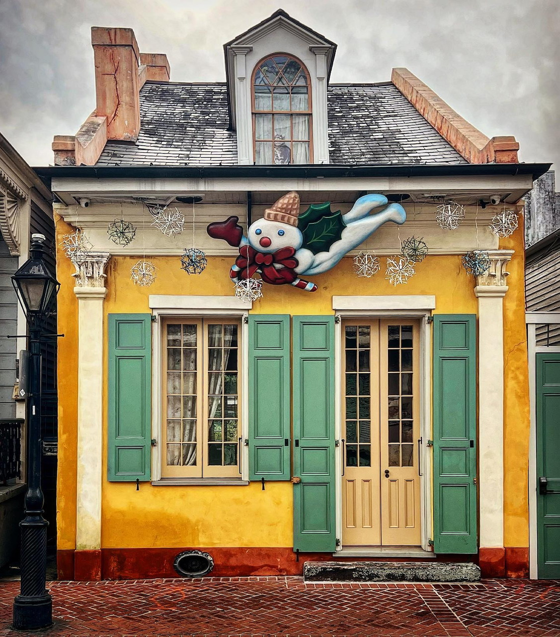 Yellow cottage with green shutters and Christmas wreath decoration on historic street