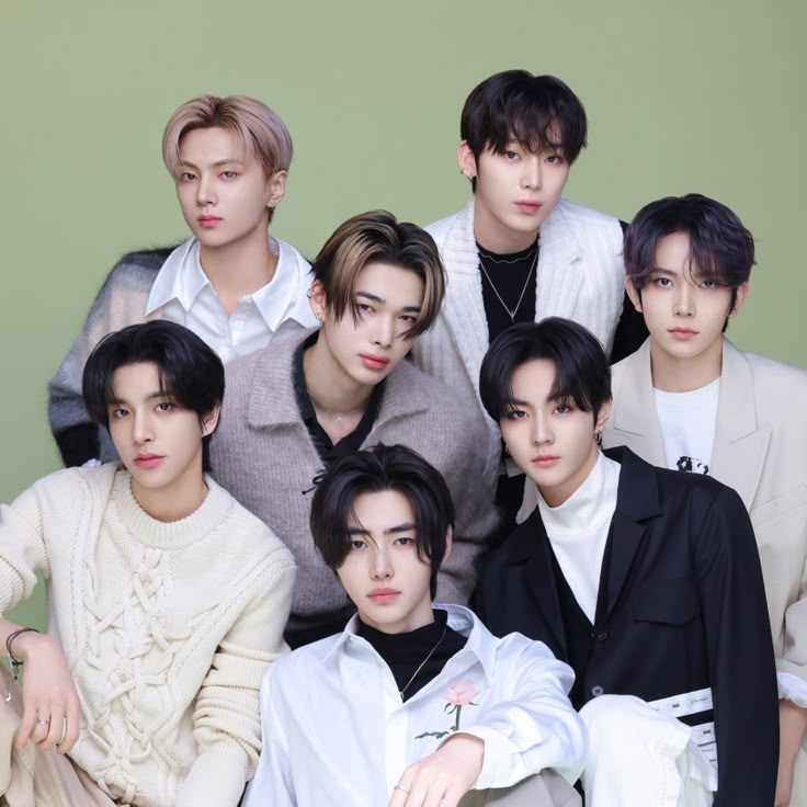 Studio portrait of seven young men posing together against a pale green background
