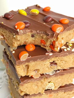 Three stacked peanut butter bars topped with chocolate and candy pieces