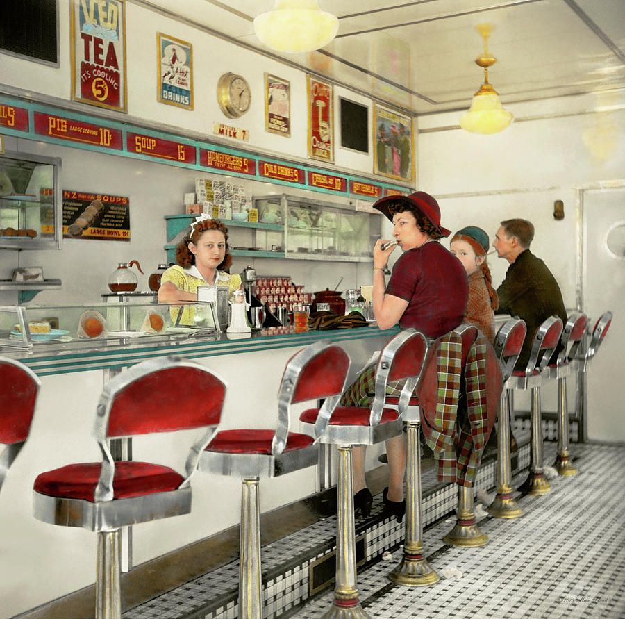 Vintage 1940s diner with red chrome stools, white counter, waitress and customers inside
