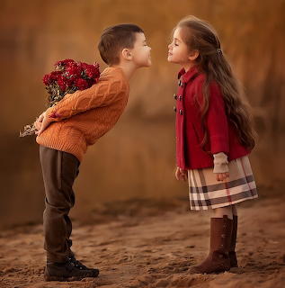 Young boy hiding flowers behind his back while leaning toward a girl outdoors