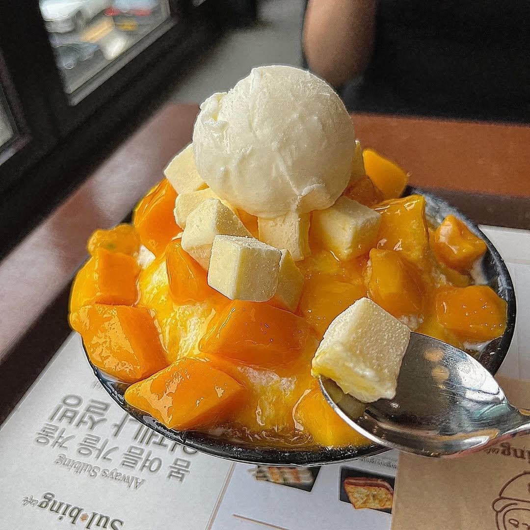 Bowl of shaved ice dessert with mango chunks and coconut toppings