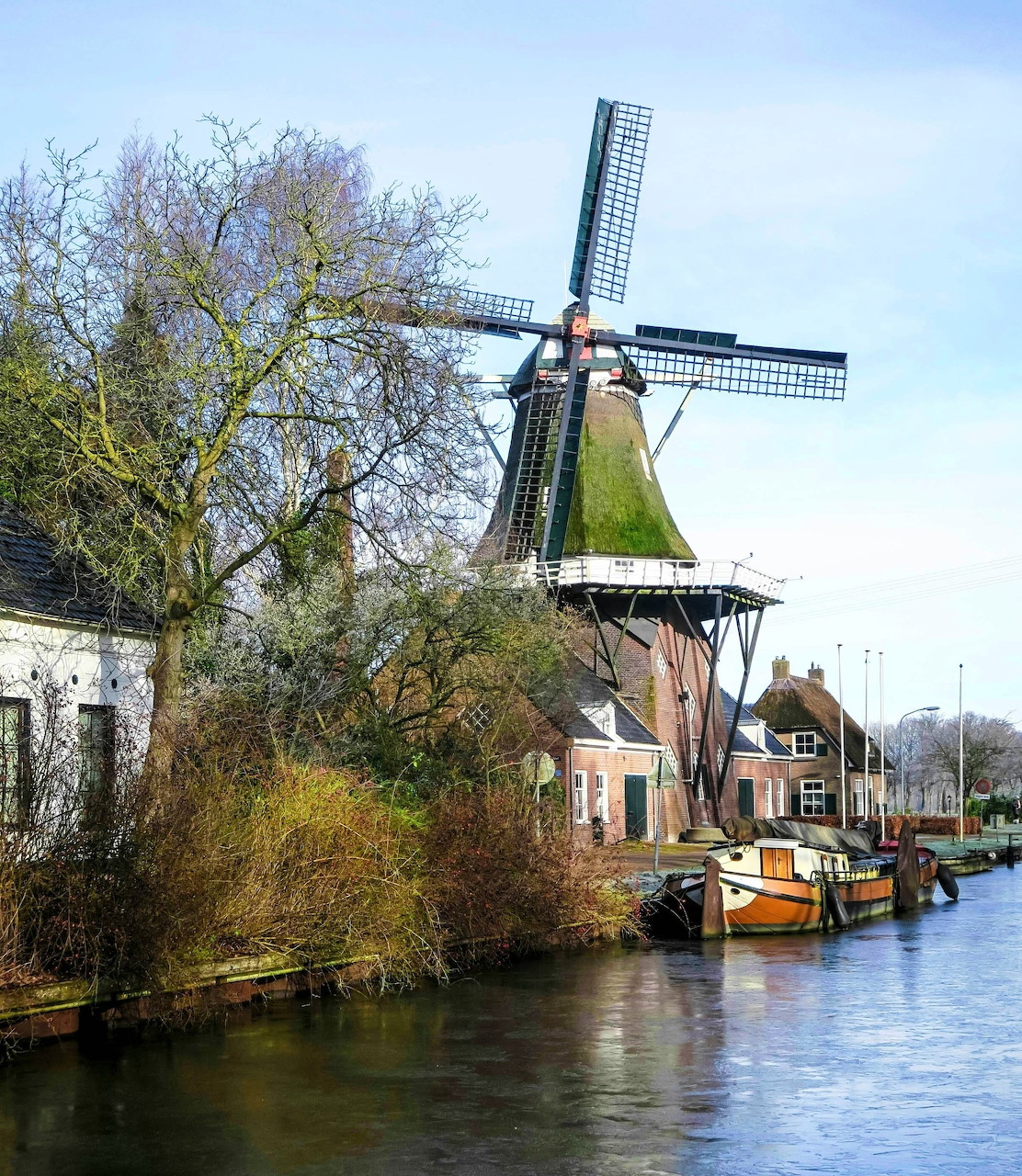 Dutch windmill on canal with trees and historic buildings reflected in water