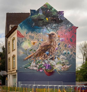 Street art mural of a bird and flowers painted on the side of a building