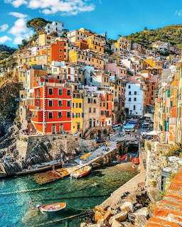 Colorful buildings of Riomaggiore village stacked on a hillside above a small boat harbor in Cinque Terre, Italy