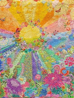Colorful handmade quilt with yellow sun, floral patterns, and embroidered details in rainbow hues